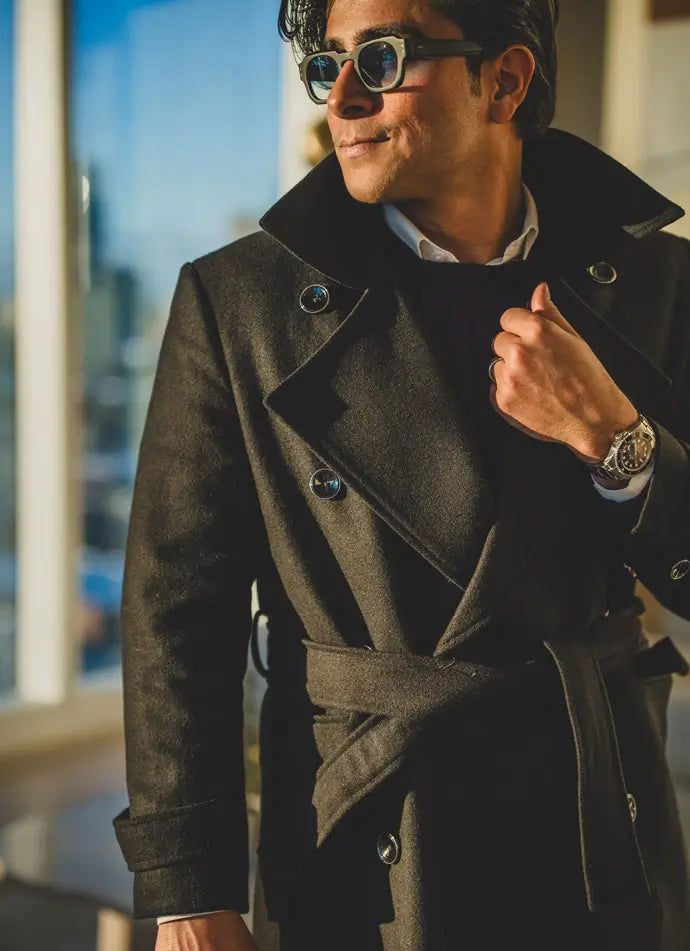 Man wearing a dark coat with a blurred cityscape background