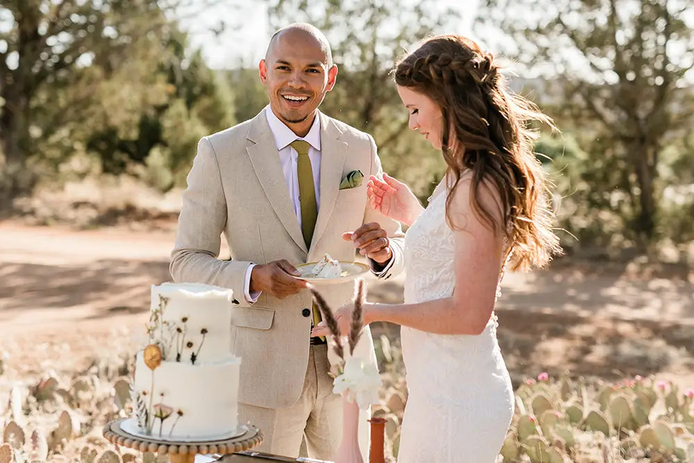 groom in linen suit with bride eating cake