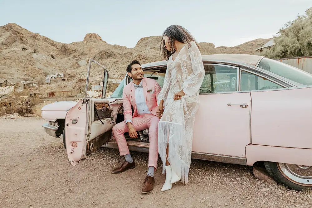 groom in salmon linen suit with bride in car