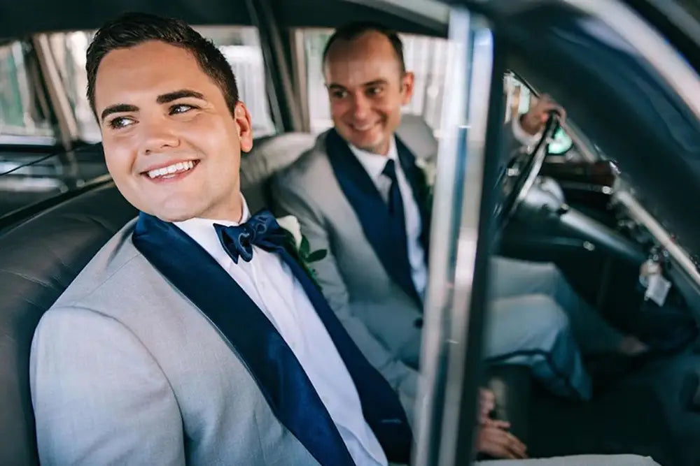 two grooms in light grey custom tuxedos in car