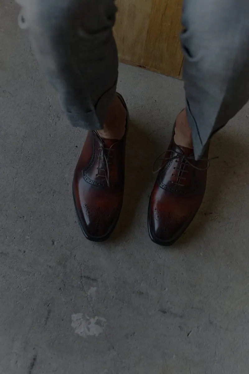 Brown leather loafers with gold hardware on a textured surface
