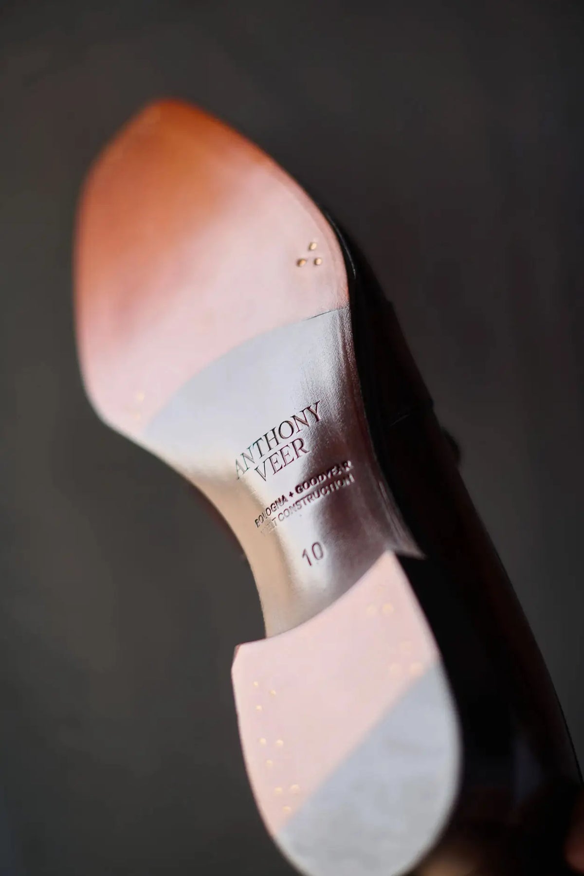 Close-up of a shoe with 'Anthony Veer' branding on a dark background