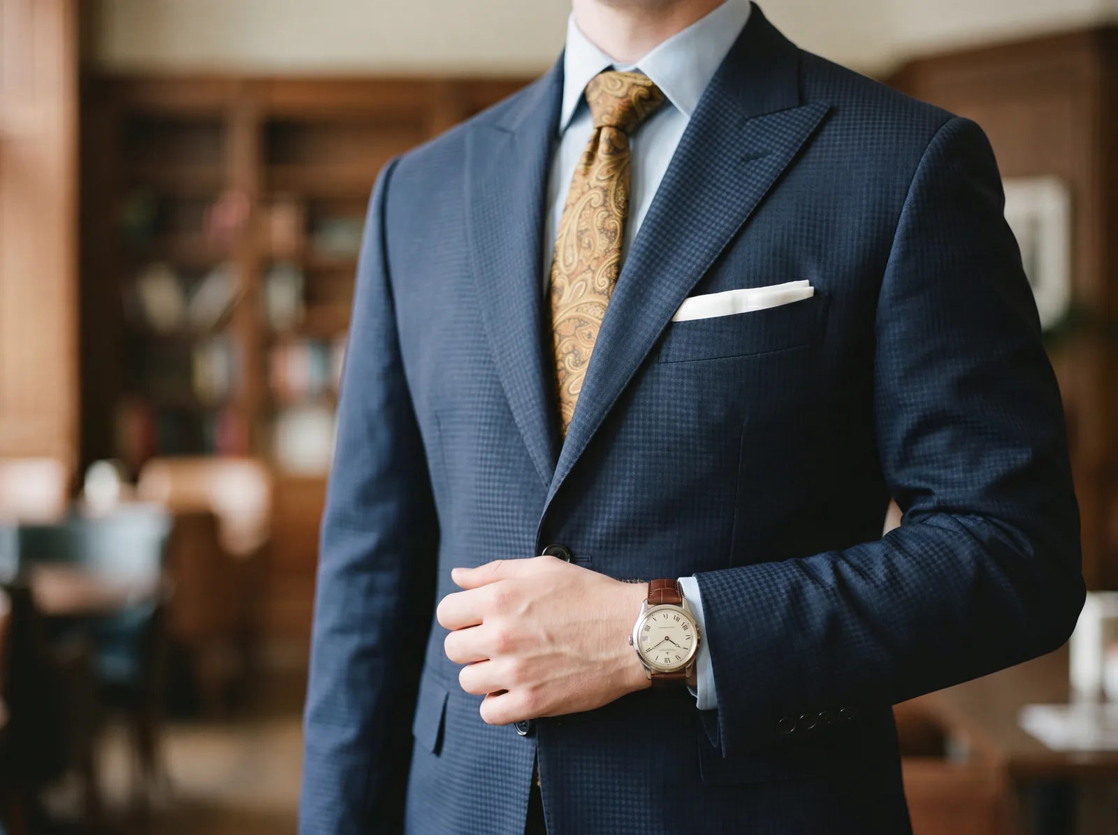A navy suit styled with a white pocket square and a wristwatch