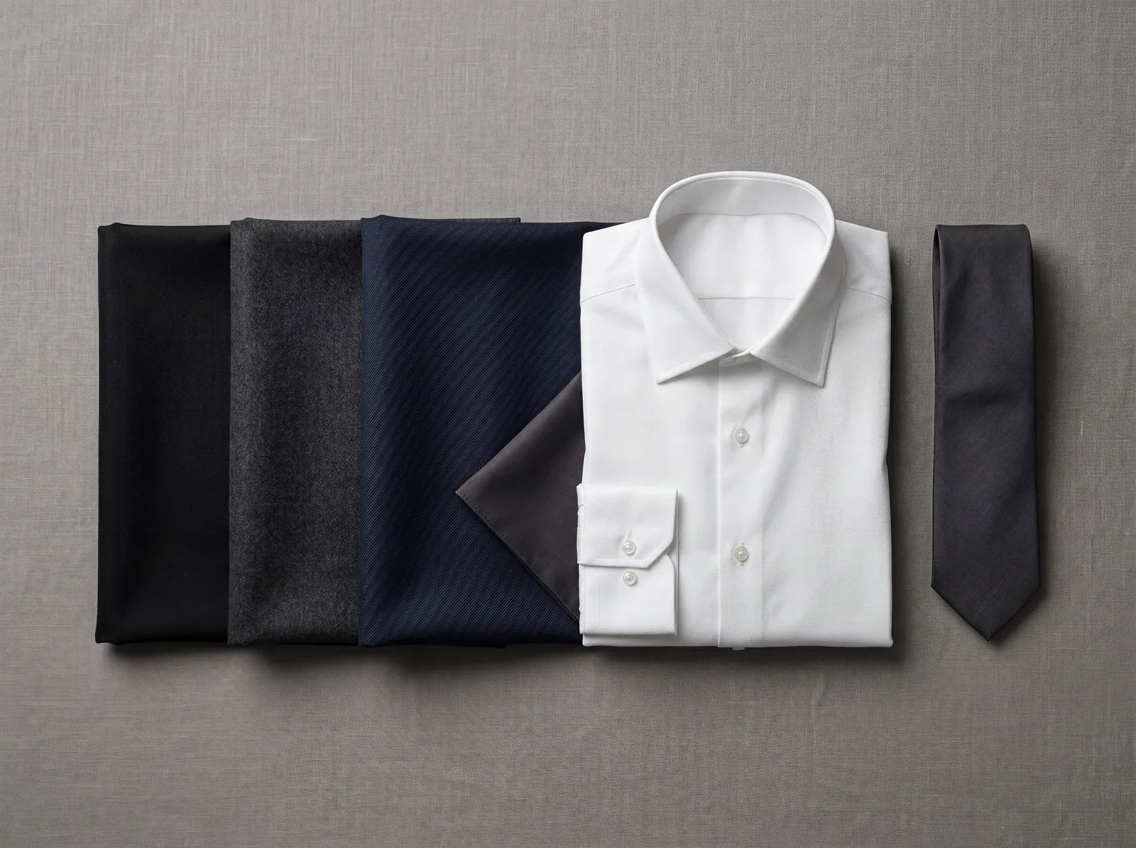 Dark suit cloths in black, charcoal and navy with a white shirt and dark tie