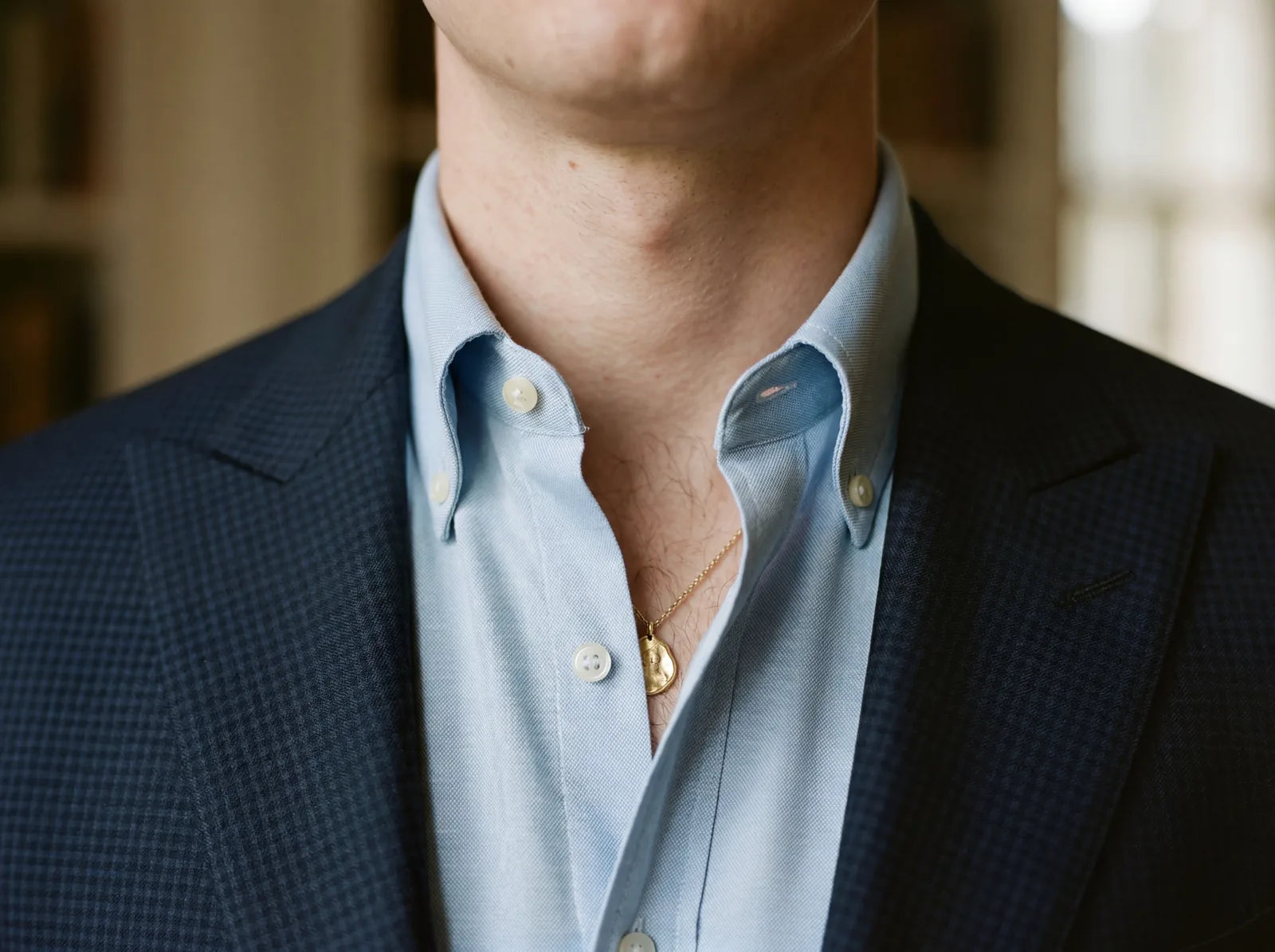Close-up of a button-down shirt collar worn open with no tie under a suit jacket