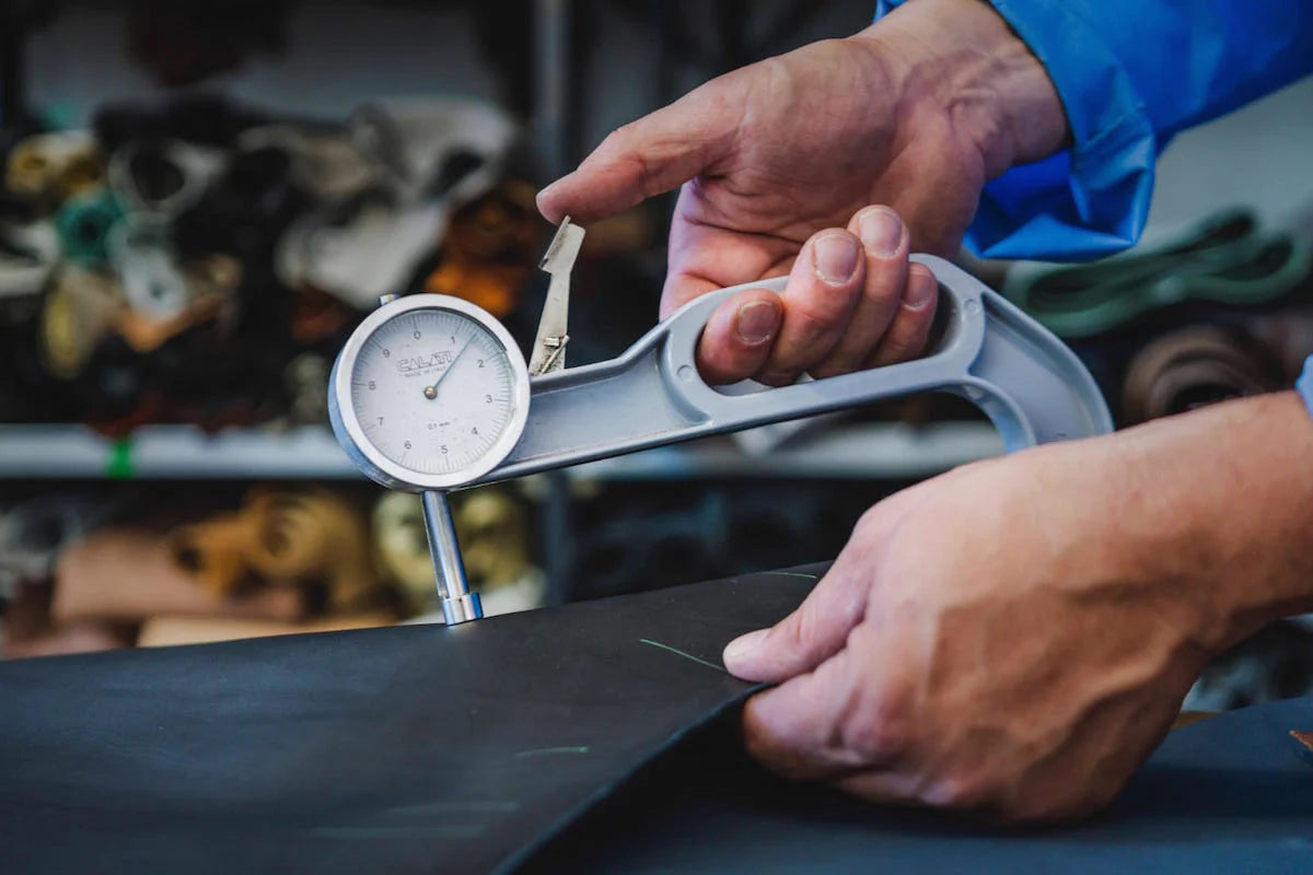 Person using a dial indicator on a piece of leather with a blurred background