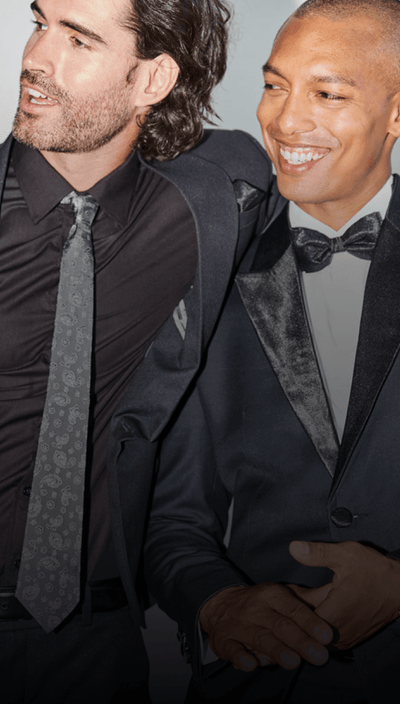 two men, one in a black suit and black tuxedo, both smiling