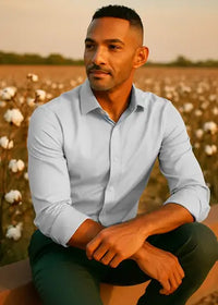 Man sitting in a field of cotton with a sunset background