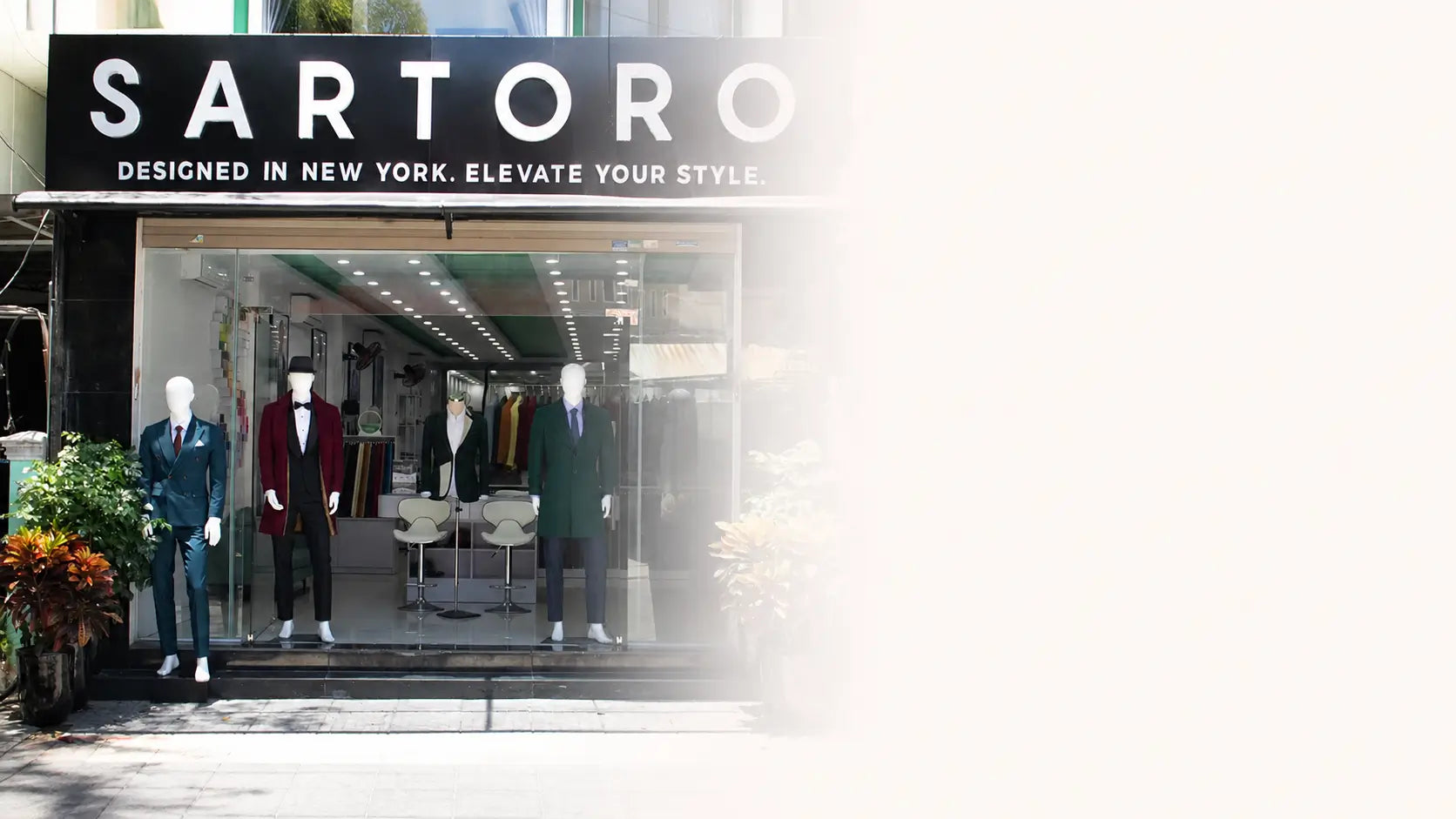Sartoro clothing store storefront with mannequins wearing suits in front of a large glass window, under a black sign reading SARTORO.