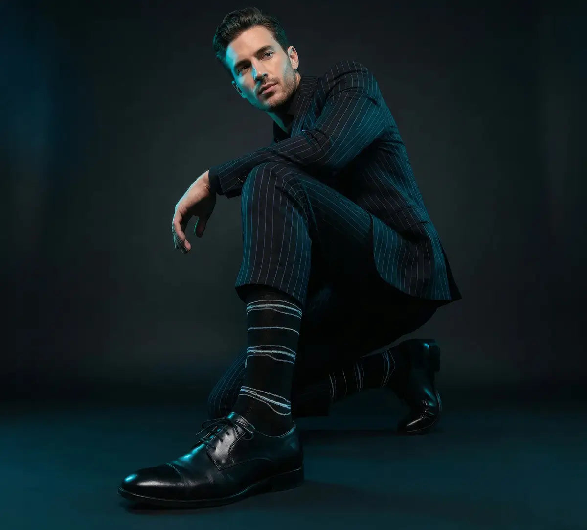 man kneeling in black suit and black socks384