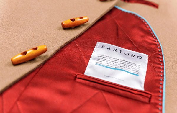 close up picture of a wool coat showing the red interior lining and sartoro patch