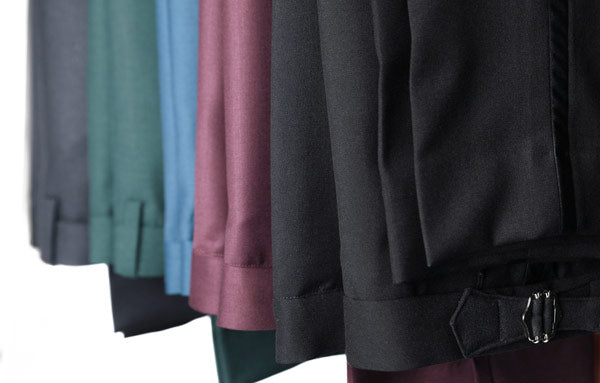 multiple pants of varying colors hanging from a rack