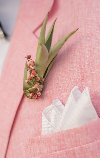 close up of a pink linen jacket with white pocket square and flower