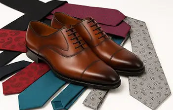 Brown dress shoes on a background of colorful ties