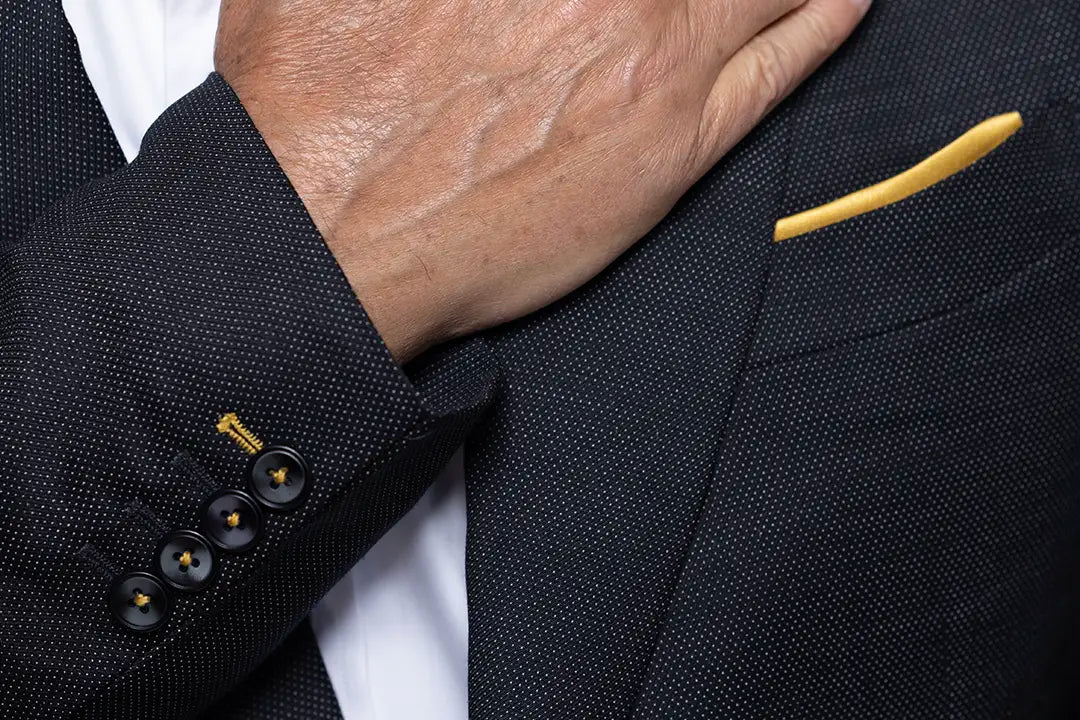 close up of pocket square and sleeve cuff in gold