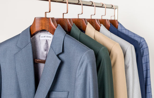 multiple suits of various colors hanging on a rack