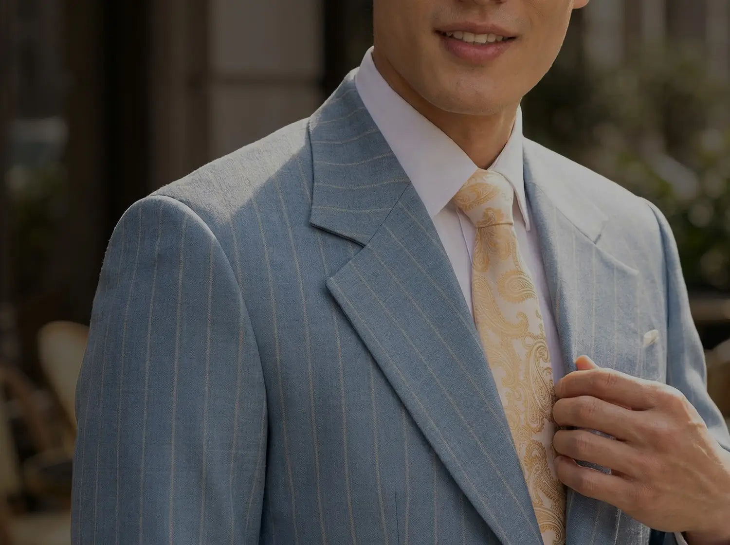 Man wearing a light blue pinstripe suit with a beige tie outdoors49