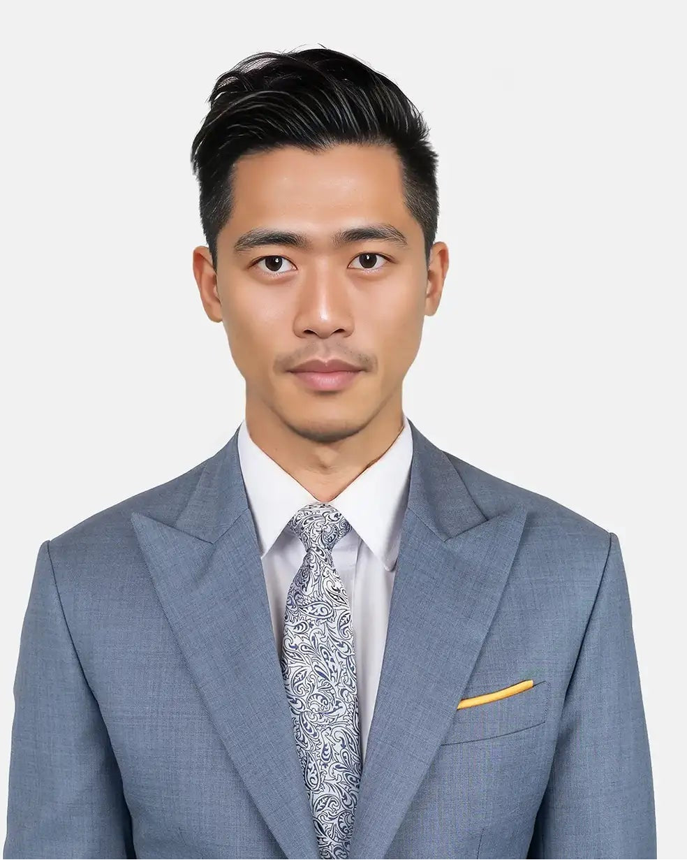 Man wearing a gray suit with a white shirt and patterned tie on a plain background