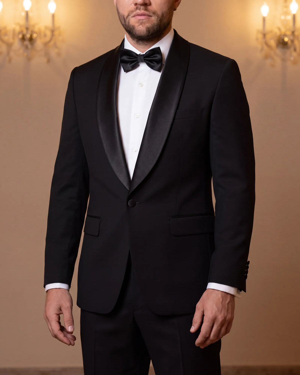 At strict black tie, wear a tuxedo. Its satin-faced lapels set it apart from a black suit.