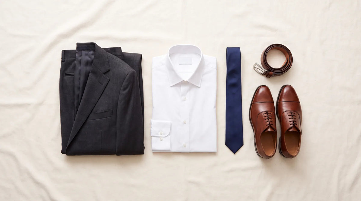 Business attire essentials: a charcoal suit, white dress shirt, navy tie, brown oxford shoes, and a belt