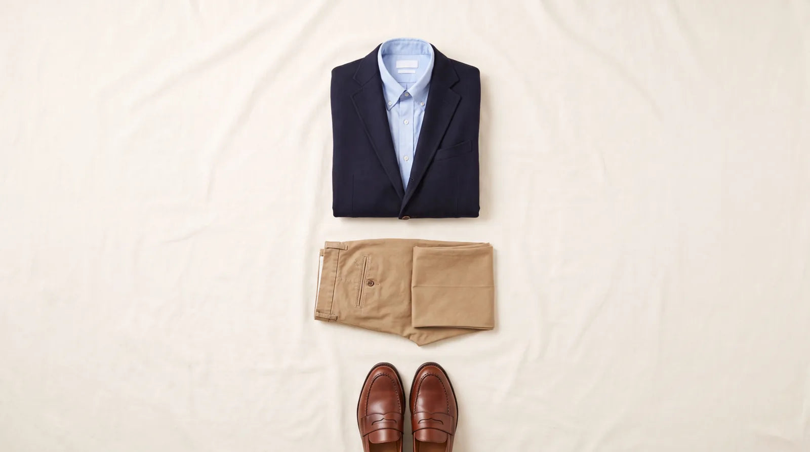 Business casual essentials: a navy blazer, light blue shirt, tan chinos, and brown loafers