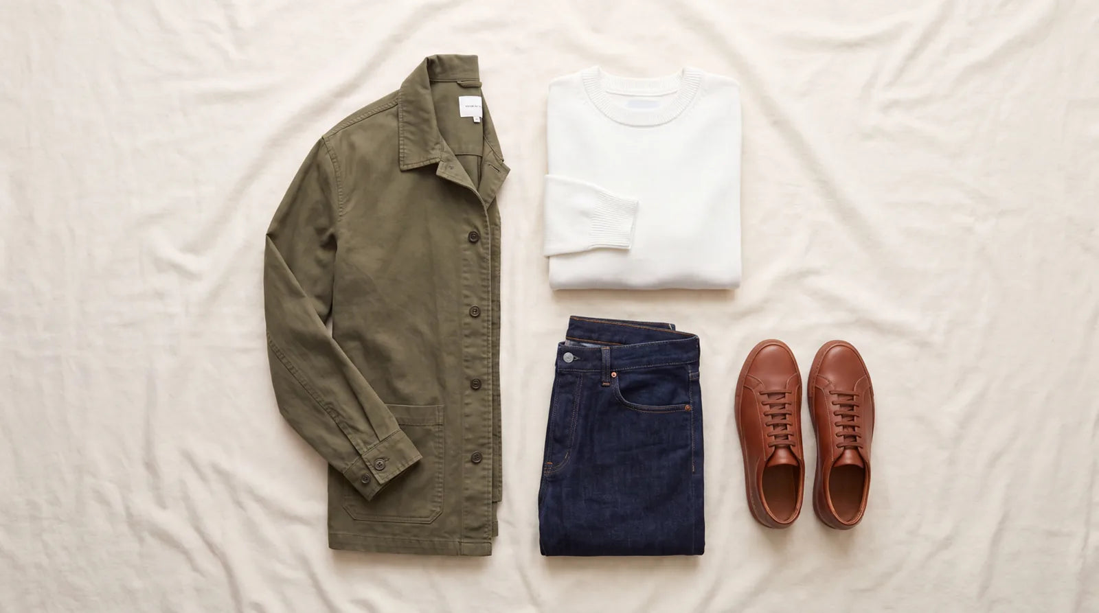 Casual menswear essentials: an overshirt, white knit, dark jeans, and brown leather sneakers