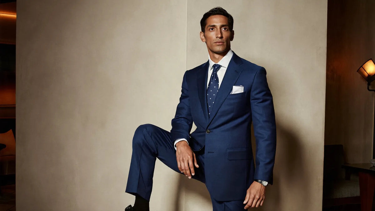 Man in a midnight blue cocktail suit with white shirt, navy silk tie, and black oxfords in an upscale lounge, every cocktail attire element executed correctly