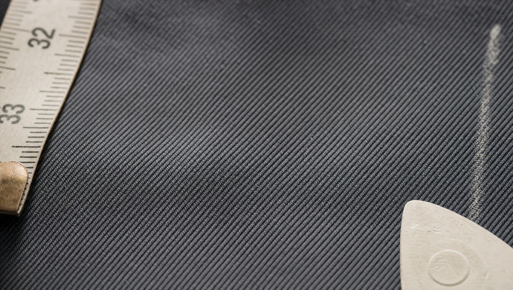 A close-up of slate grey twill weave reveals the diagonal thread structure that gives grey suiting its depth and texture beyond flat worsted wool.