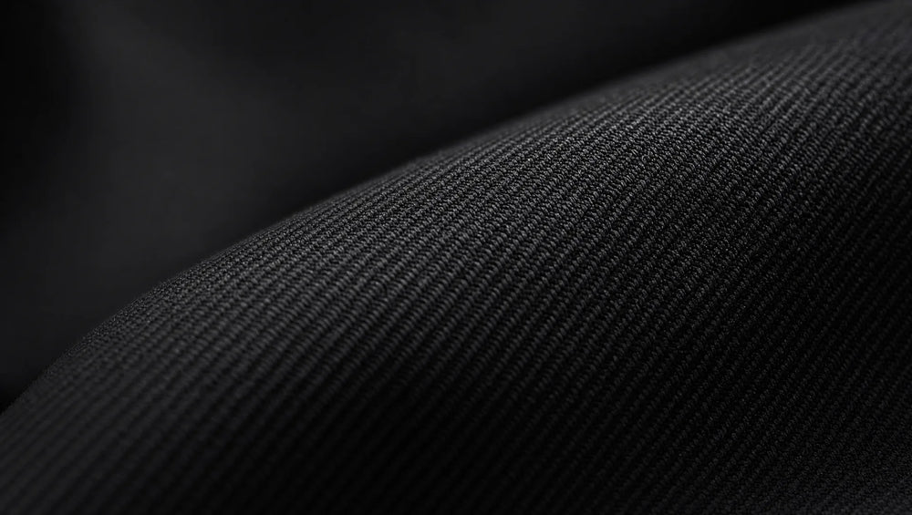 Flat worsted wool in jet black — the smooth, dense weave catches light as a subtle sheen rather than texture, which is why fabric quality matters more in black than any other suit color