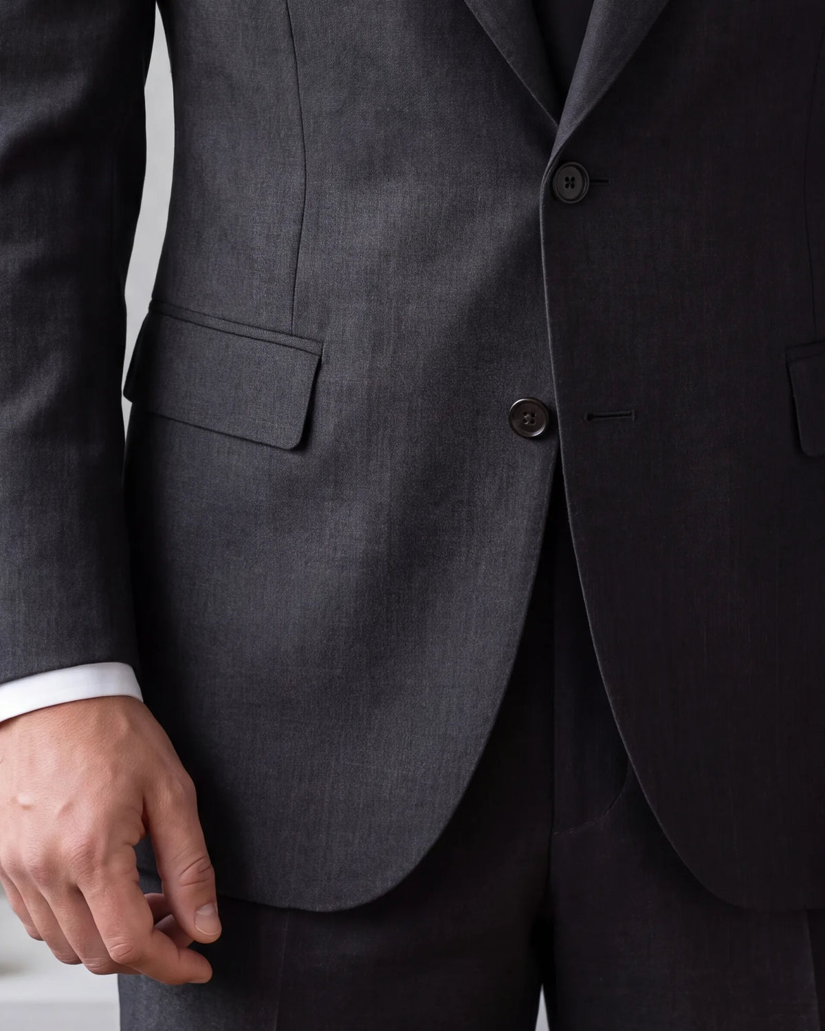 This charcoal jacket closes flat, with a little white cuff below the sleeve. Check both before the day.