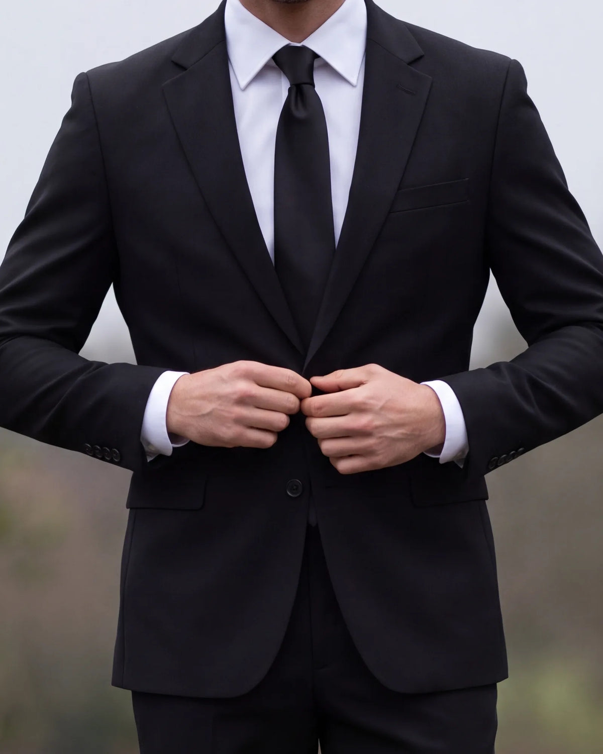 A pallbearer keeps the jacket buttoned during the carry, with the tie held by a tie bar or tucked in.