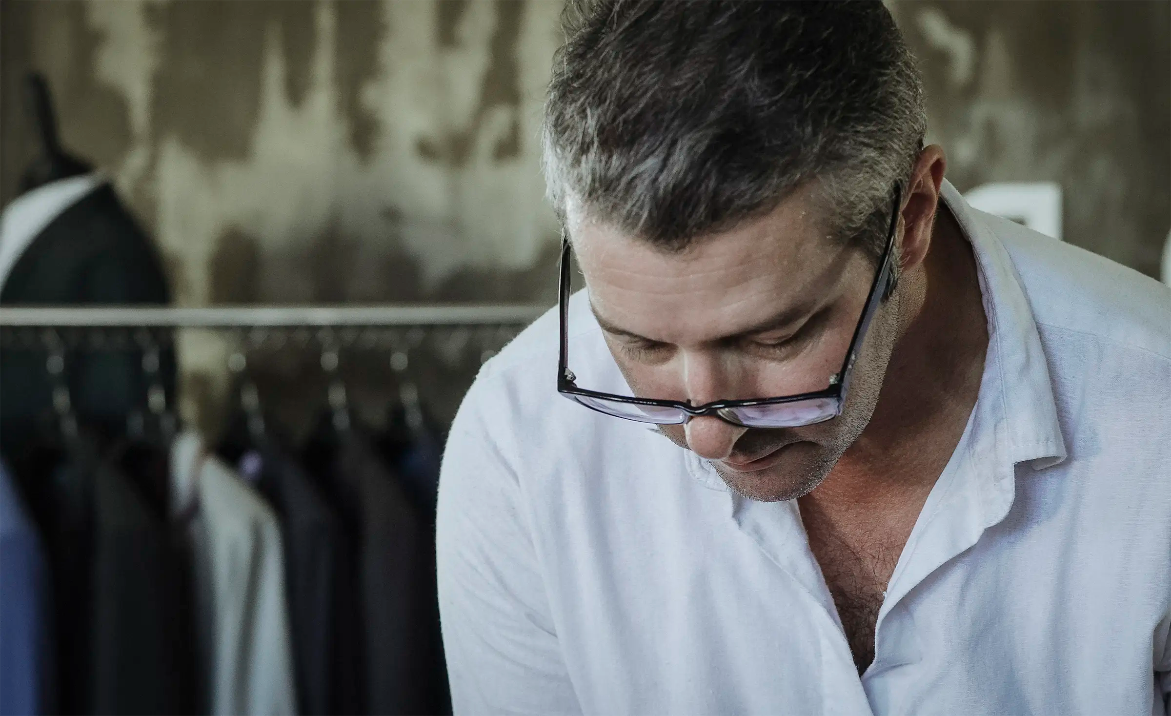 a tailor with glasses looking down at a table