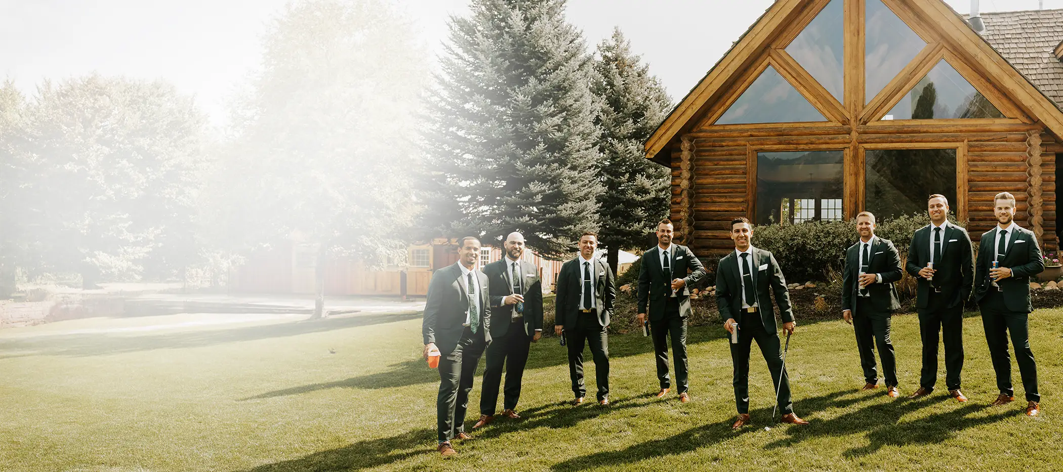 Groomsmen in green suits standing on a lawn