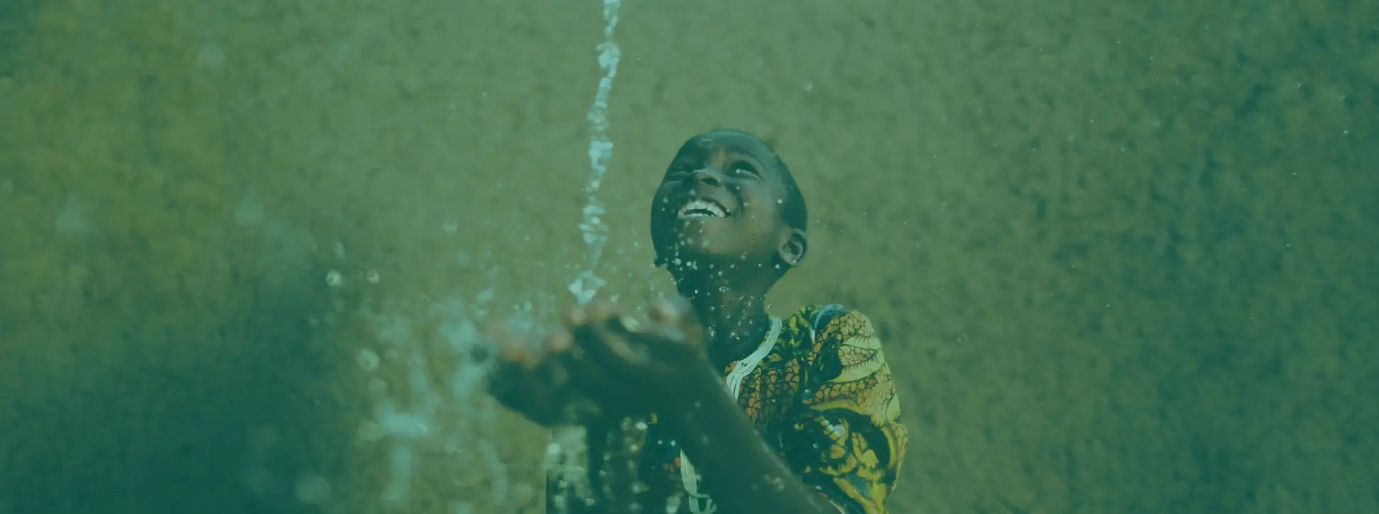 little boy smiling as water pours from above