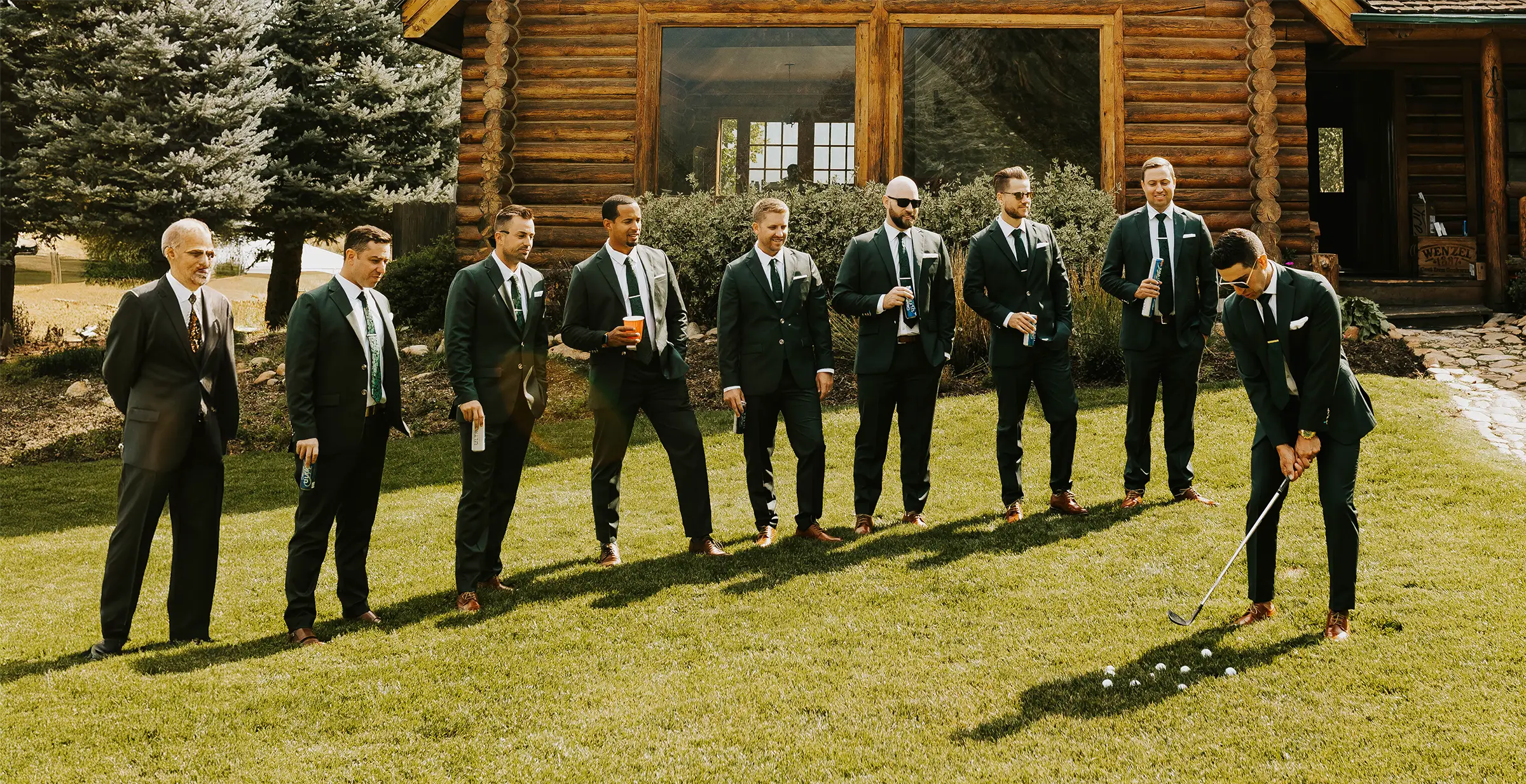 groomsmen in green suits standing outside on a lawn