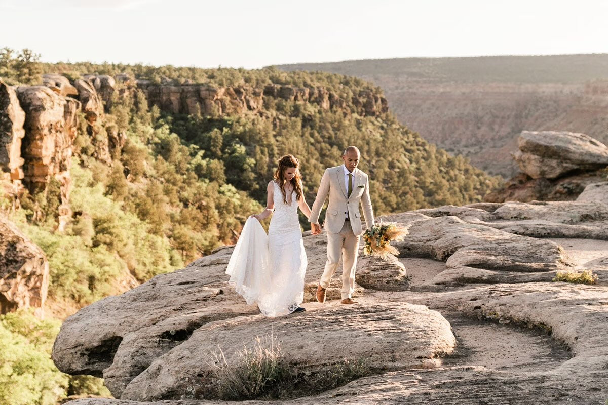 bride and groom walking across rocks in zion national park