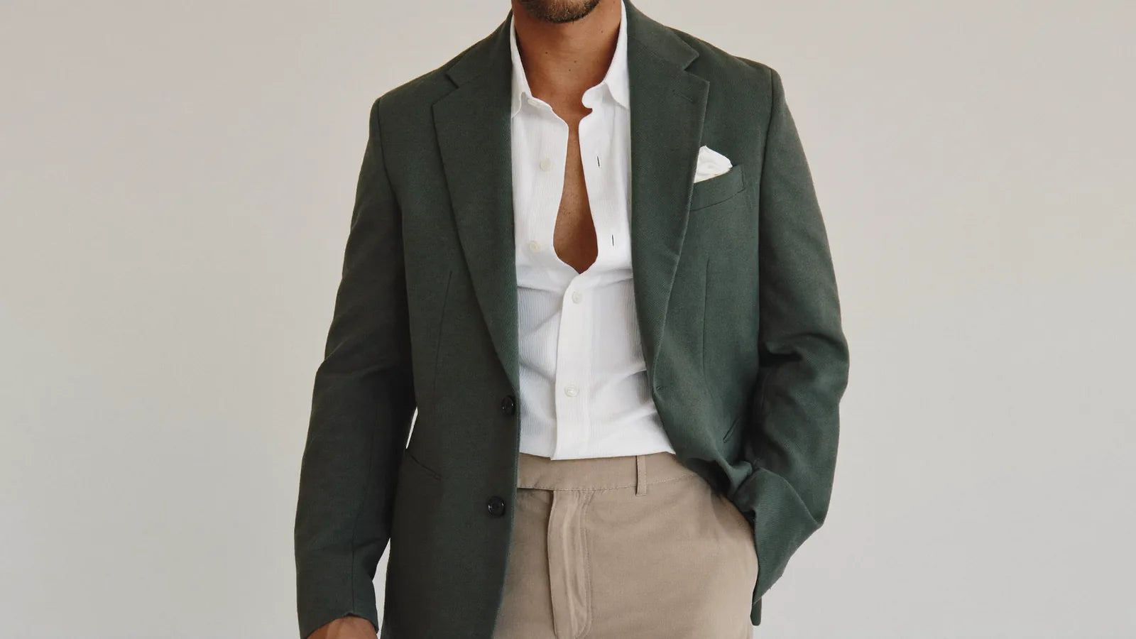 A green suit jacket worn as a sport coat over a white shirt and chinos