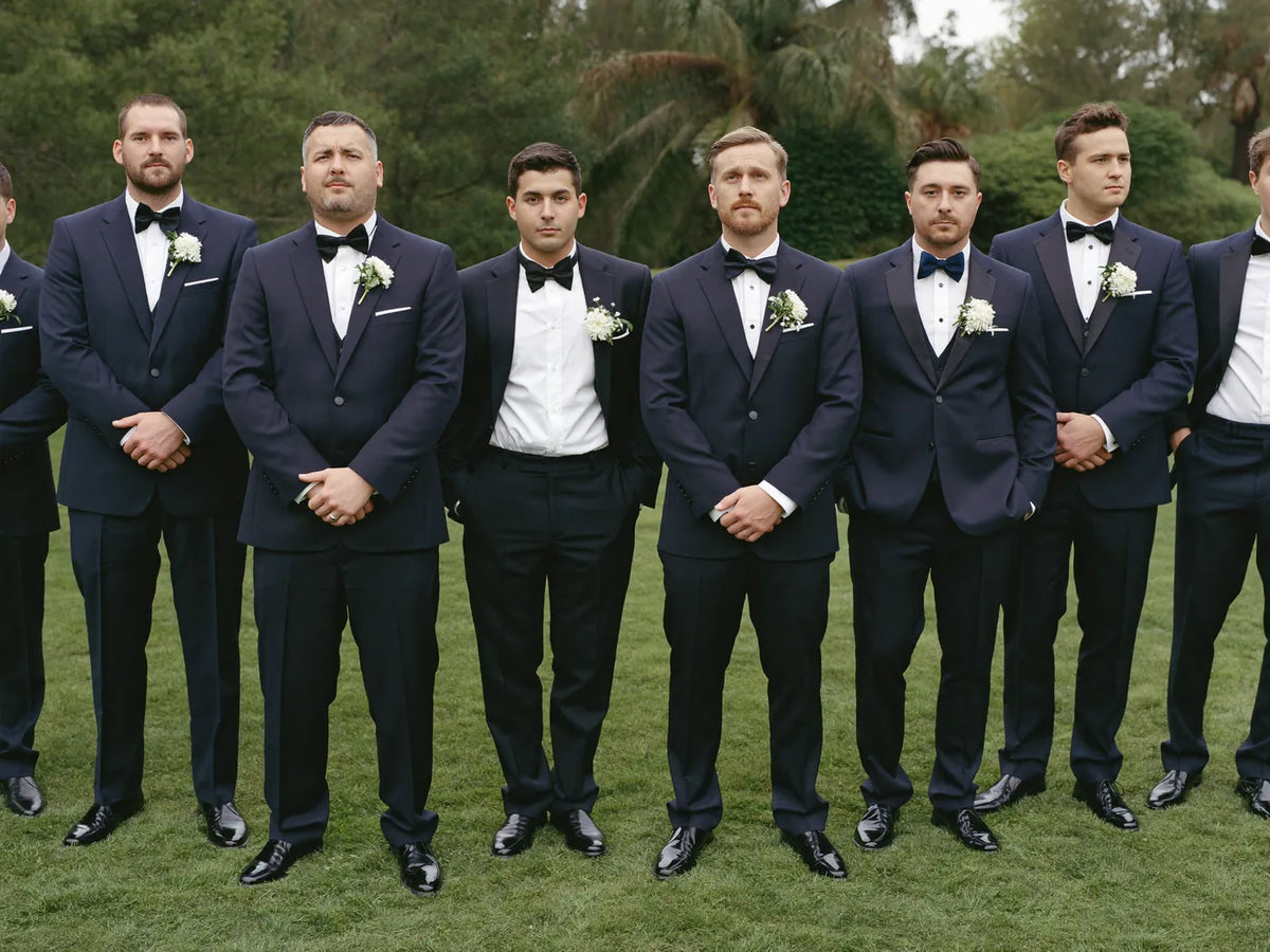 A row of groomsmen in matching navy suits with boutonnieres
