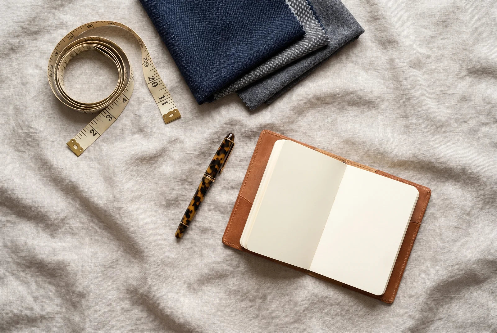 Tailor's tape measure, fabric swatches, and a notebook for planning groomsmen suits