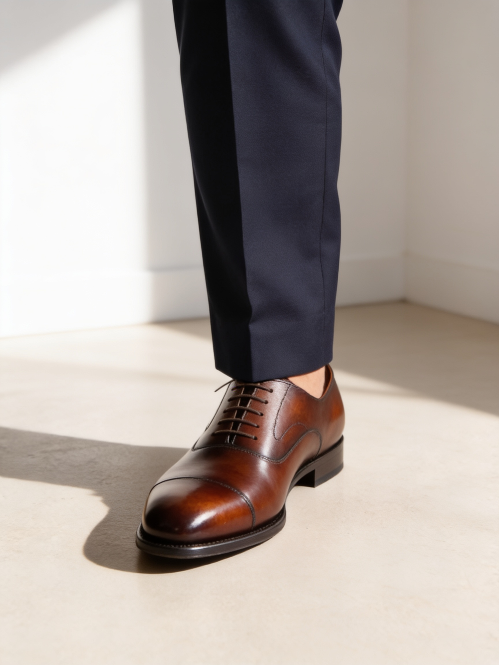 A dark brown cap-toe oxford worn with navy suit trousers for daytime and business.