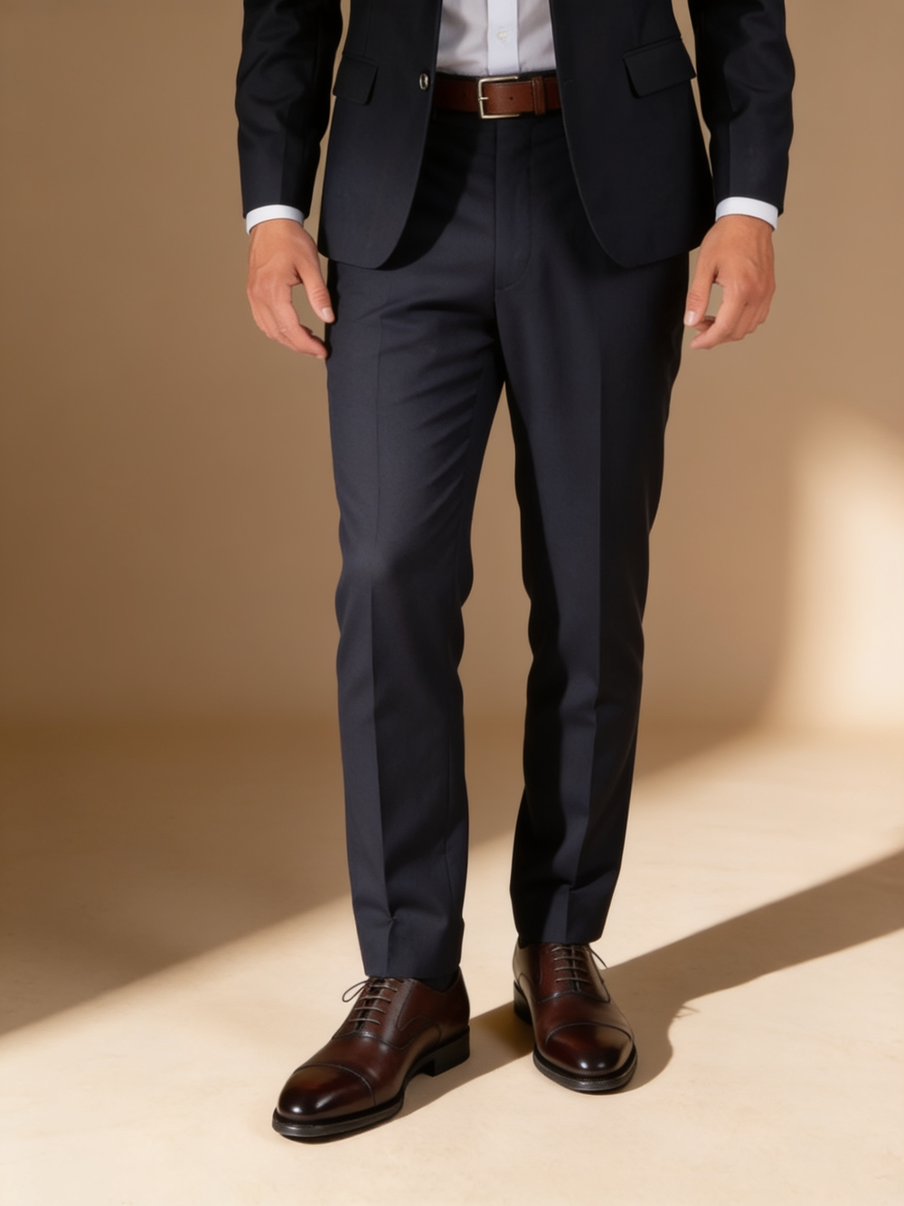 A navy suit worn with dark brown cap-toe oxford shoes and a matching brown belt.