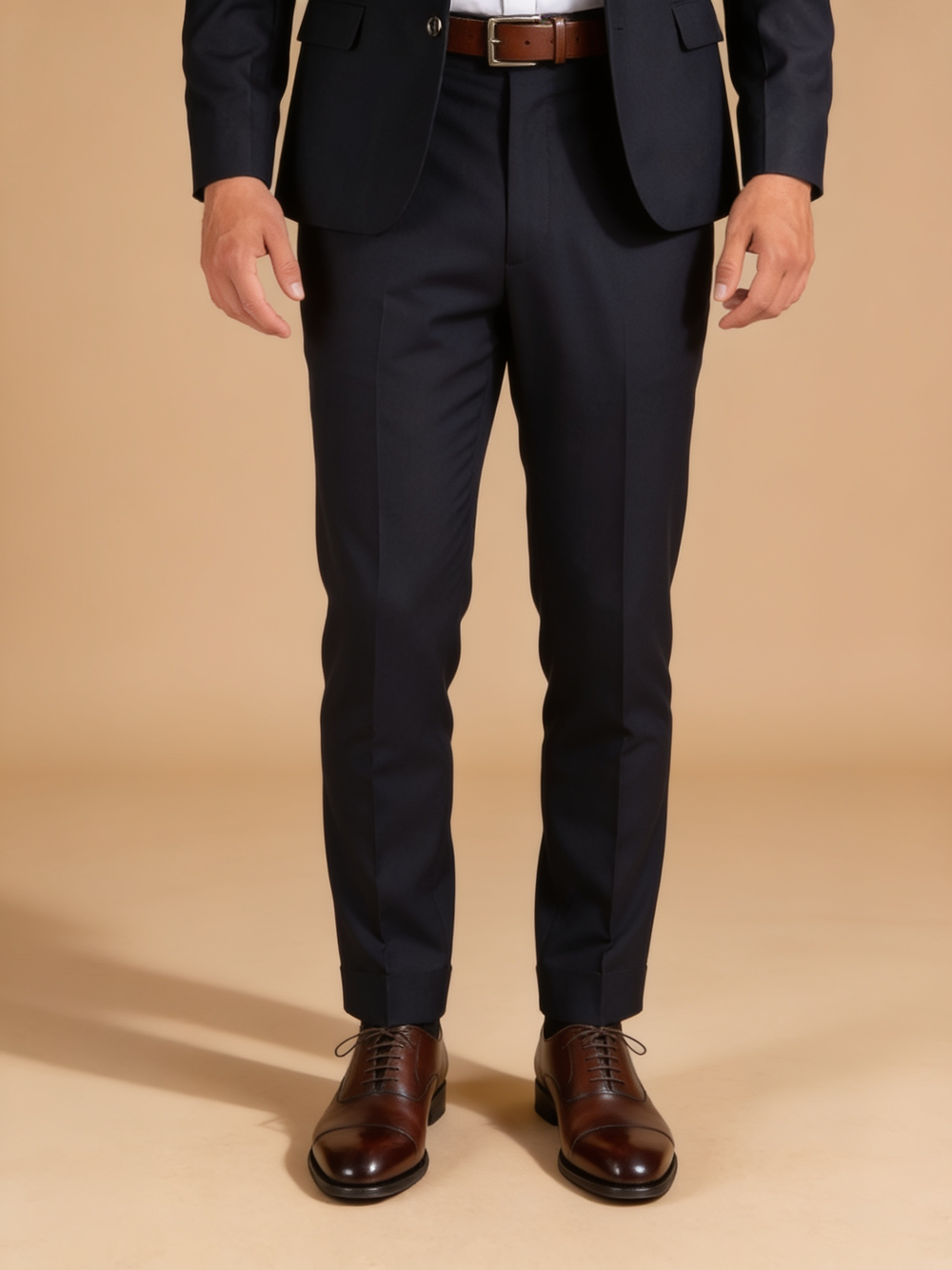 A brown leather belt worn with matching brown oxford shoes in the same shade and finish.