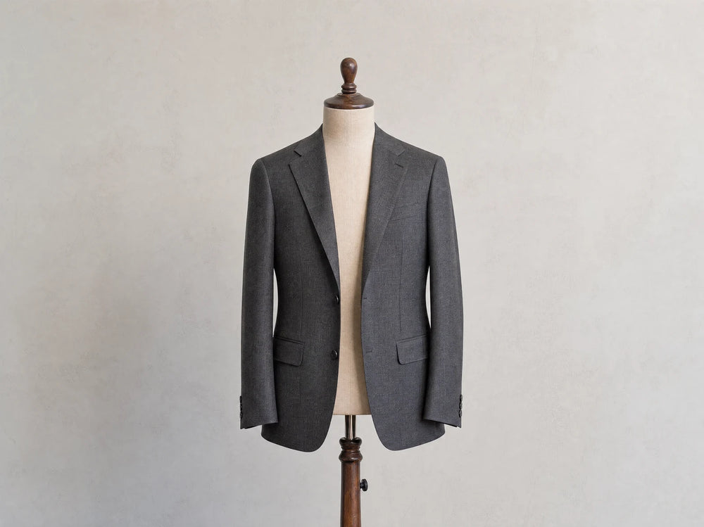Charcoal men's suit jacket on a tailor's form, introducing the parts of jacket anatomy