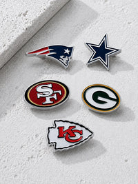 Five NFL team enamel pins, including New England Patriots, Dallas Cowboys, San Francisco 49ers, Green Bay Packers, and Kansas City Chiefs logos, arranged on a textured light gray surface.