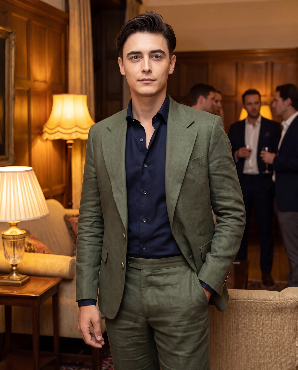 Man in a juniper green suit with a dark shirt at an evening gathering
