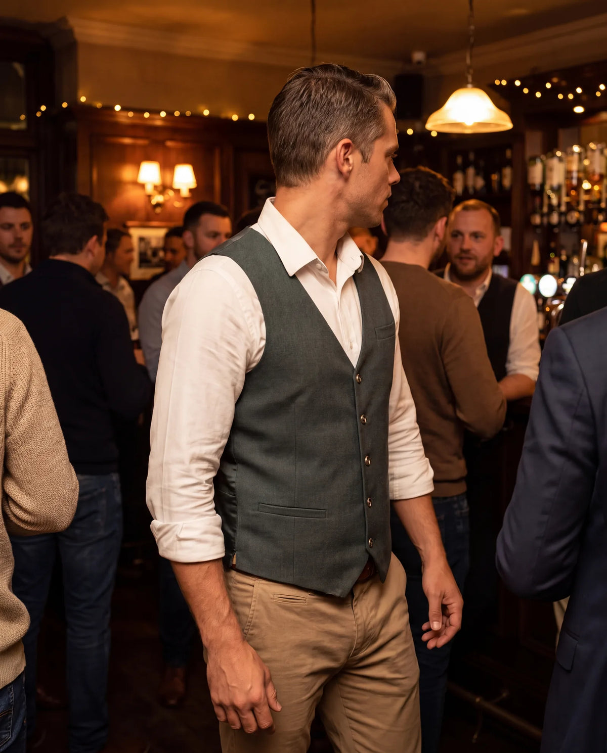 Man wearing a vest over a white shirt at a crowded evening party