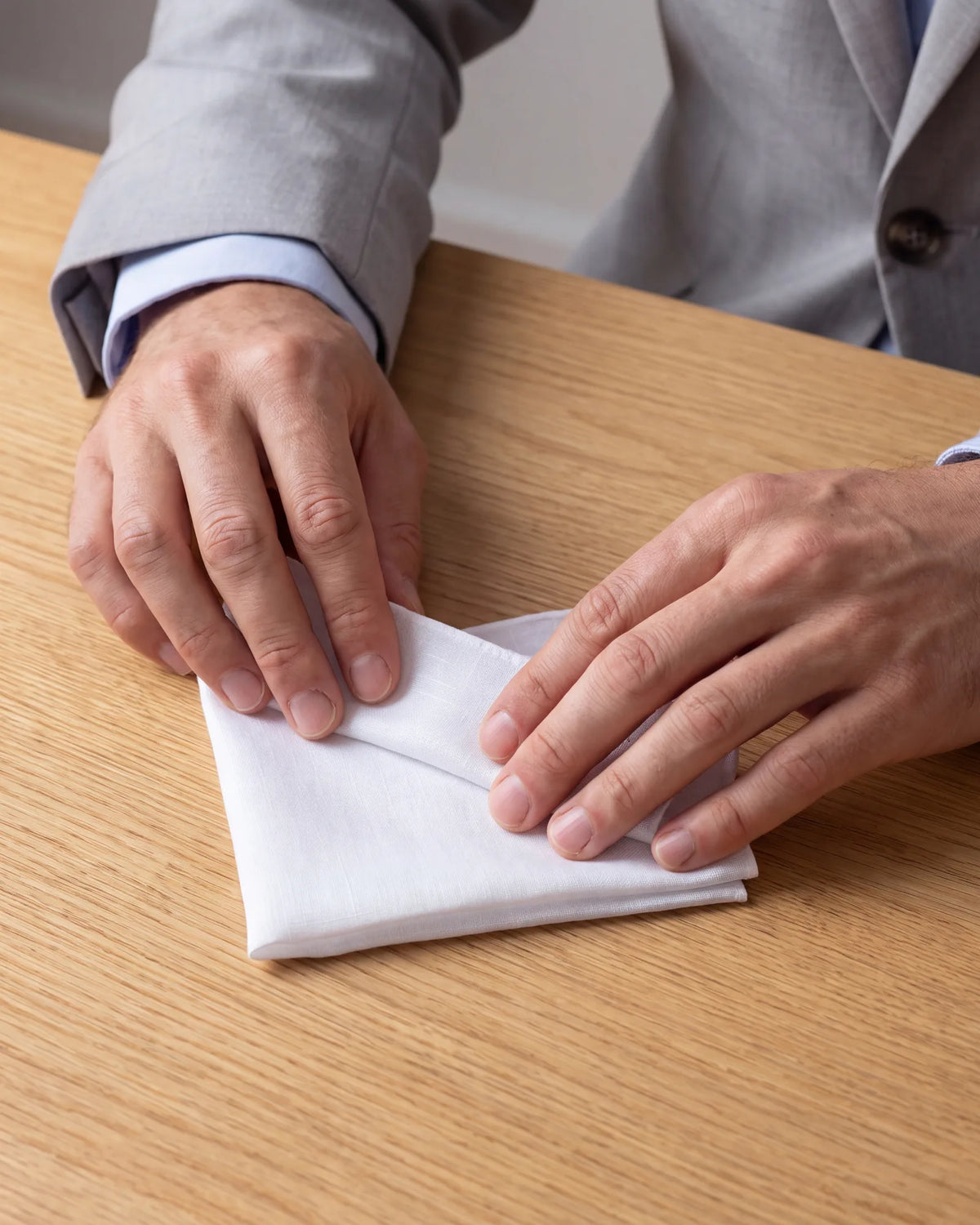Fold the square just narrow enough to slide into the pocket. A snug fit stays put and does not stretch the jacket.