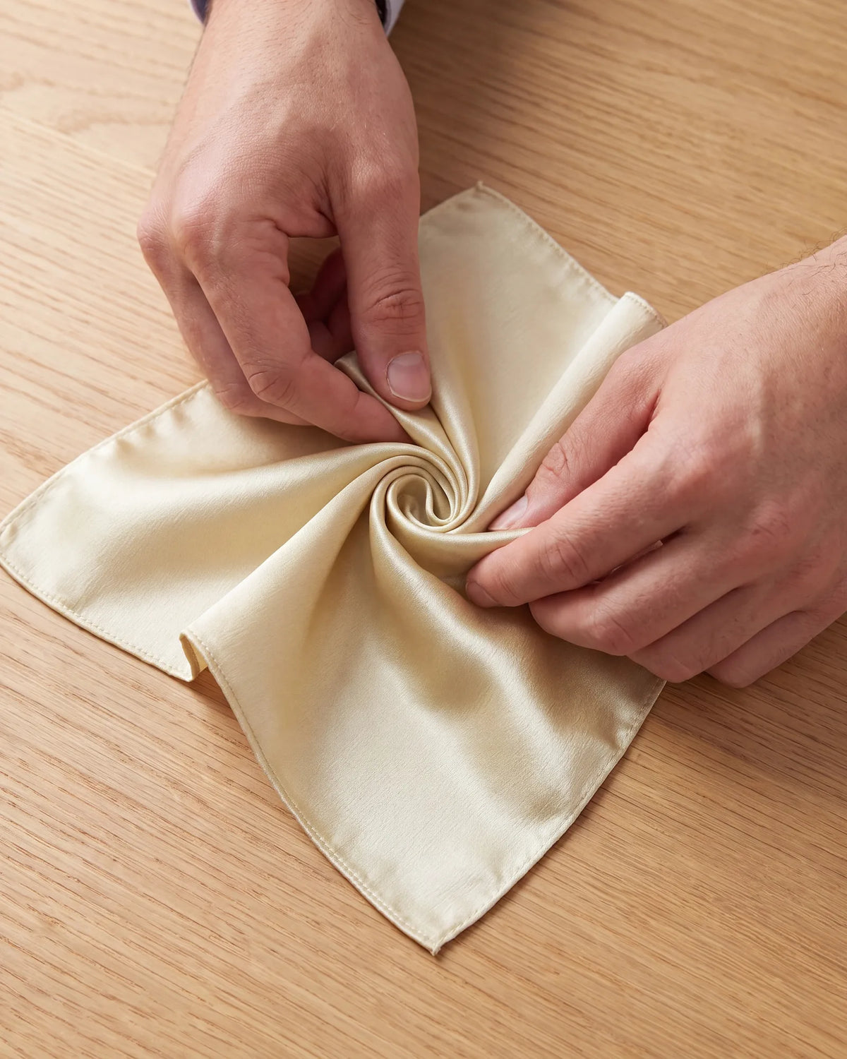 Twist the center several times until the fabric winds into a tight spiral. The loose corners then fold under it to make the base.