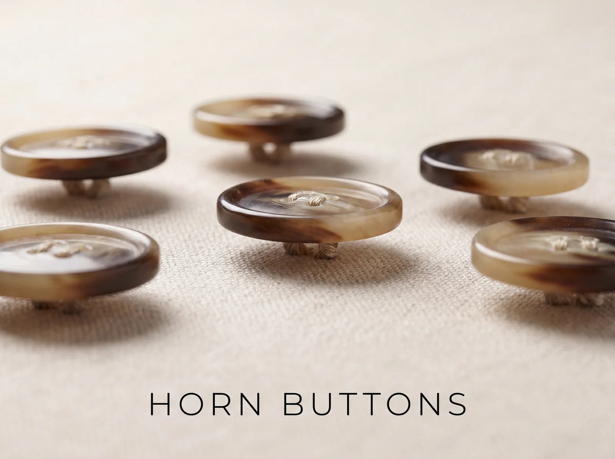 Genuine horn suit buttons with thread shanks resting on wool cloth