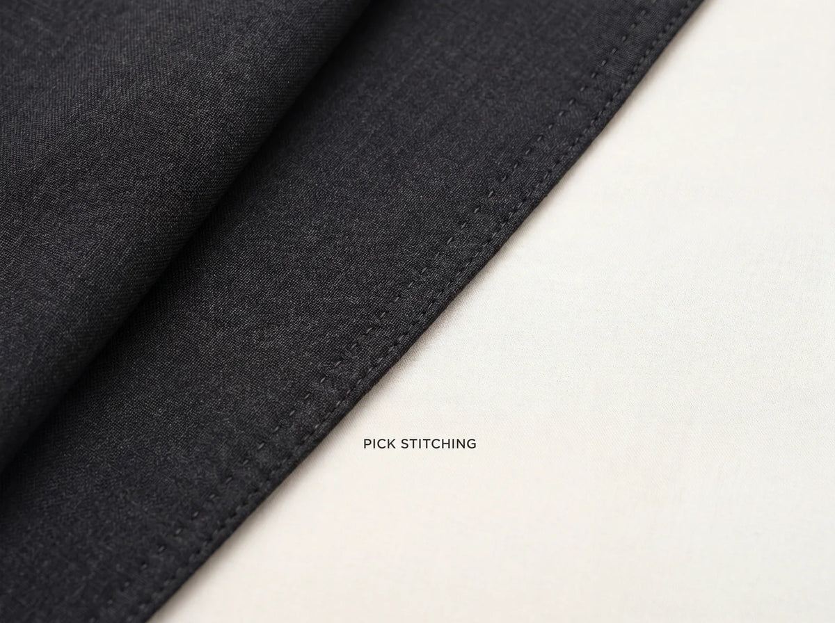 Pick stitching running a quarter inch inside a charcoal suit lapel edge